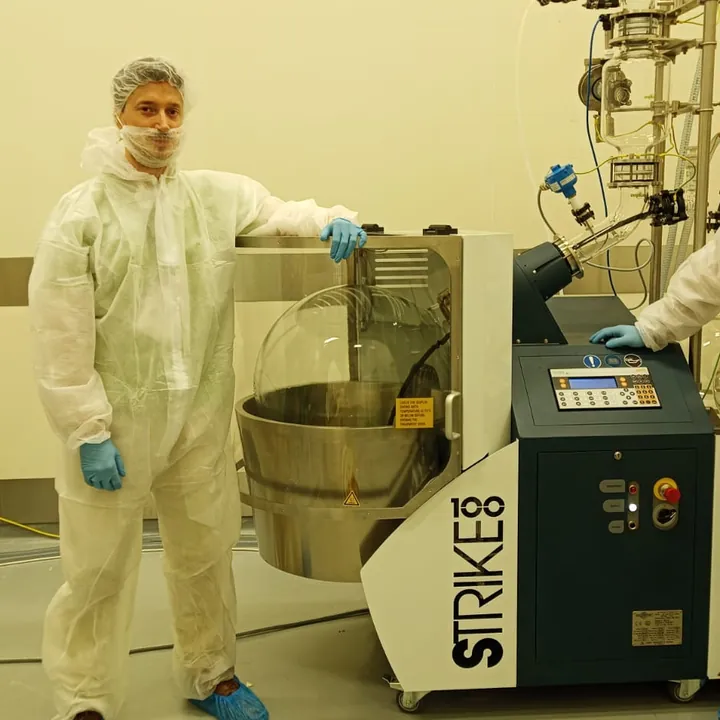 Guy Entract in a cleanroom suit beside an industrial rotary evaporator