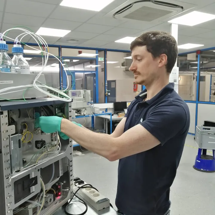 Guy Entract in gloves working inside an open HPLC instrument